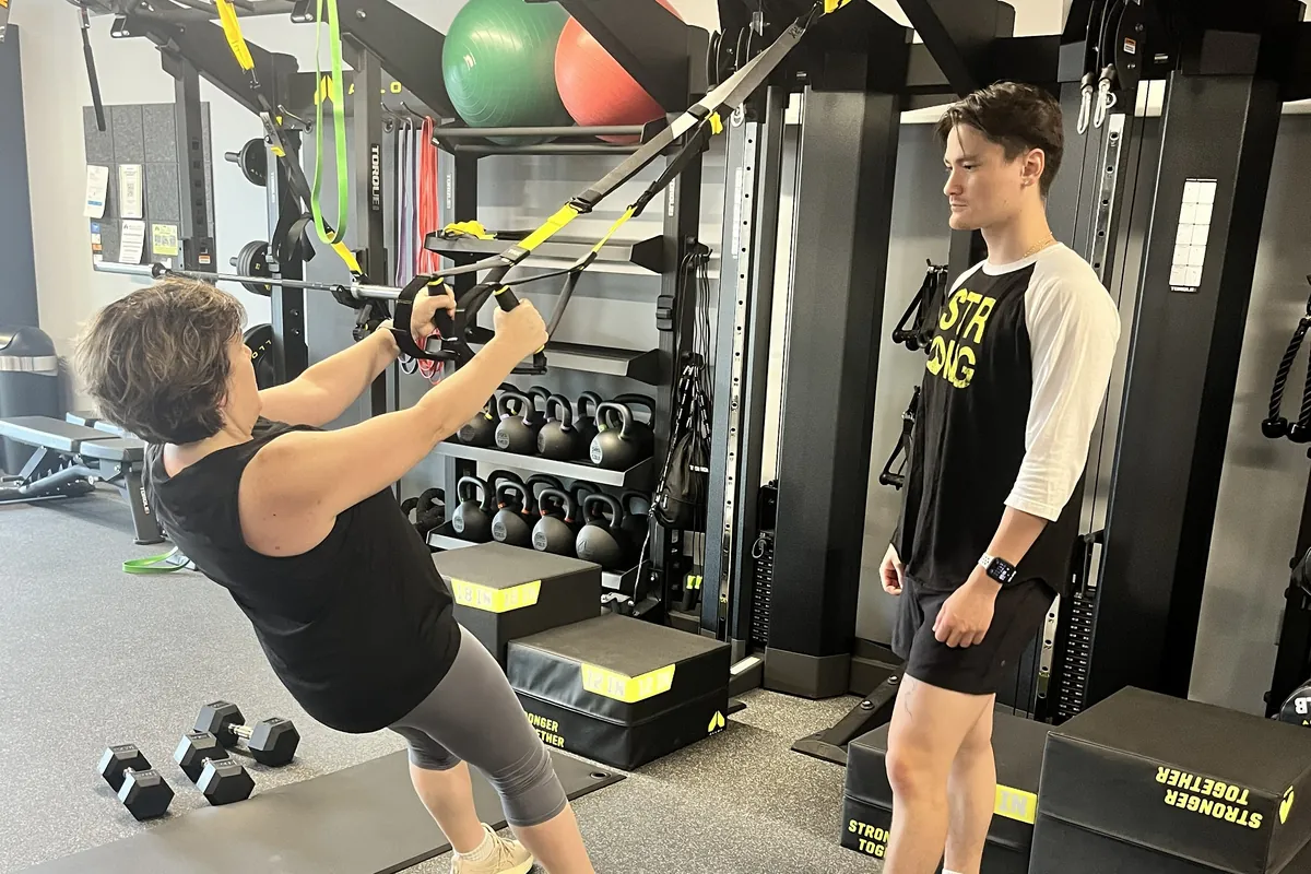 Coach guiding a member through a TRX row at Alloy Personal Training Fairfax City